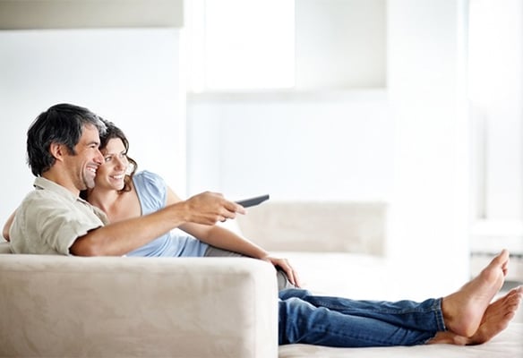 man and woman lying on a couch watching tv